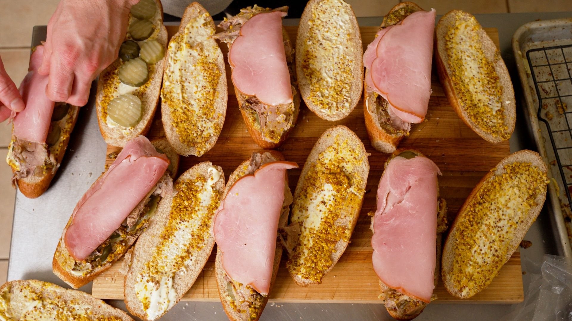 Sandwiches being built with ham, pickles and whole-grain SRSLY GOOD mustard